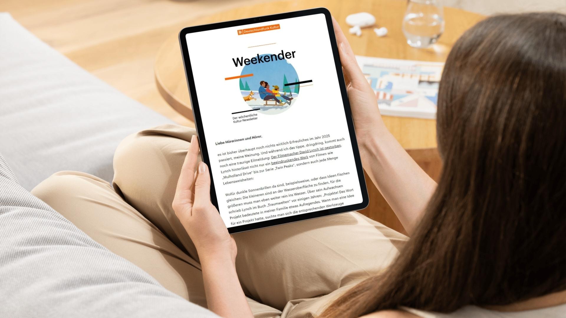 Eine junge Frau sitzt auf einem Sofa und hält ein Tablet in den Händen, sie liest den Deutschlandfunk Kultur-Newsletter "Weekender"