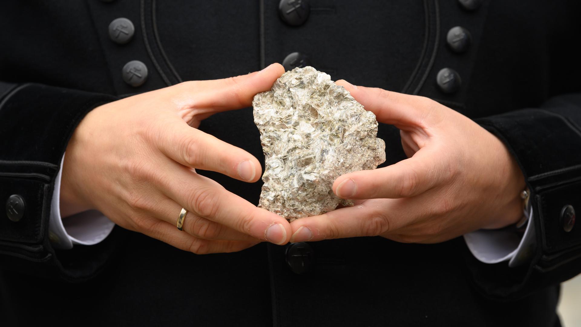 Ein Stück mit Lithium durchsetztes Stück Erz aus Sachsen wird in den Händen gehalten.