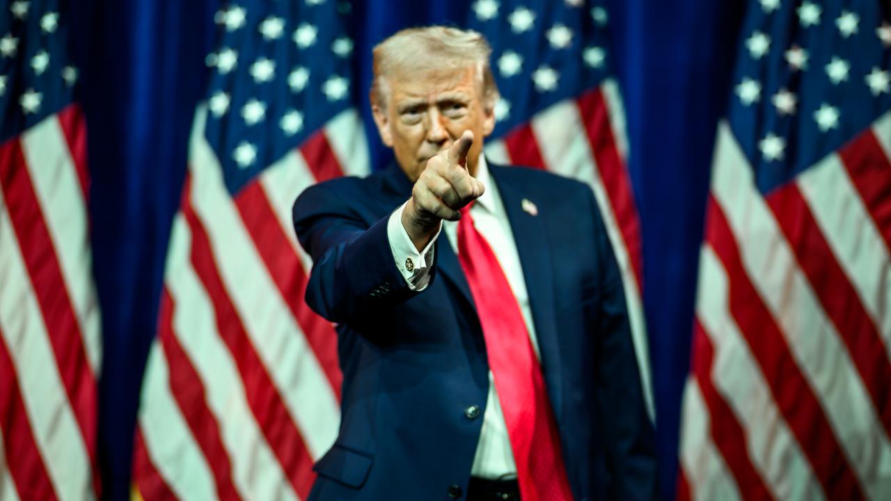 US-Präsident Donald Trump hat den rechten Arm gehoben und deutet mit dem Zeigefinger nach vorne. Im Hintergrund sind mehrere US-Faggen zu sehen. US-Präsident Donald Trump hat den rechten Arm gehoben und deutet mit dem Zeigefinger nach vorne. Im Hintergrund sind mehrere US-Faggen zu sehen.