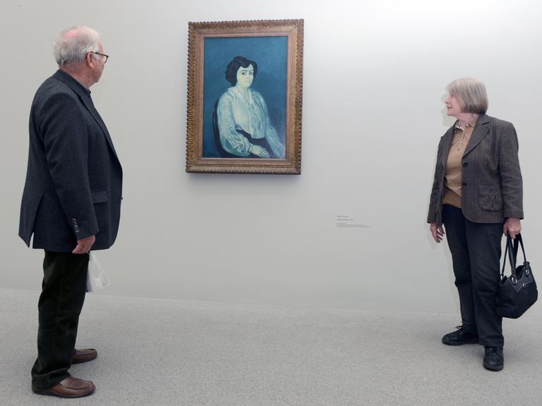 Zwei Besucher betrachten in einer Ausstellung das Gemälde "Madame Soler" (1903) von Pablo Picasso.