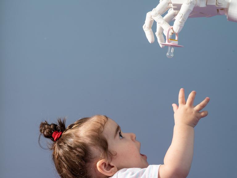 Eine humanoide Roboterhand gibt einem Baby einen Schnuller.