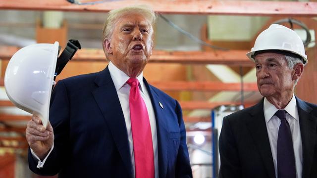 US-Präsident Donald Trump spricht bei einem Besuch der US-Notenbank mit einem weißen Bauhelm in der Hand. Jerome Powell, Vorsitzender der Federal Reserve, hört zu. 