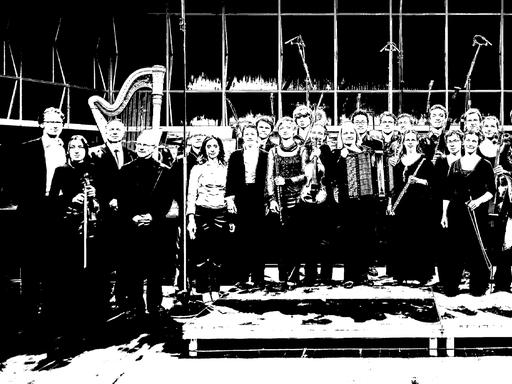 Das Ensemble steht mit seinen Instrumenten auf der Bühne und lacht auf einem schwarz-weiß-Foto.