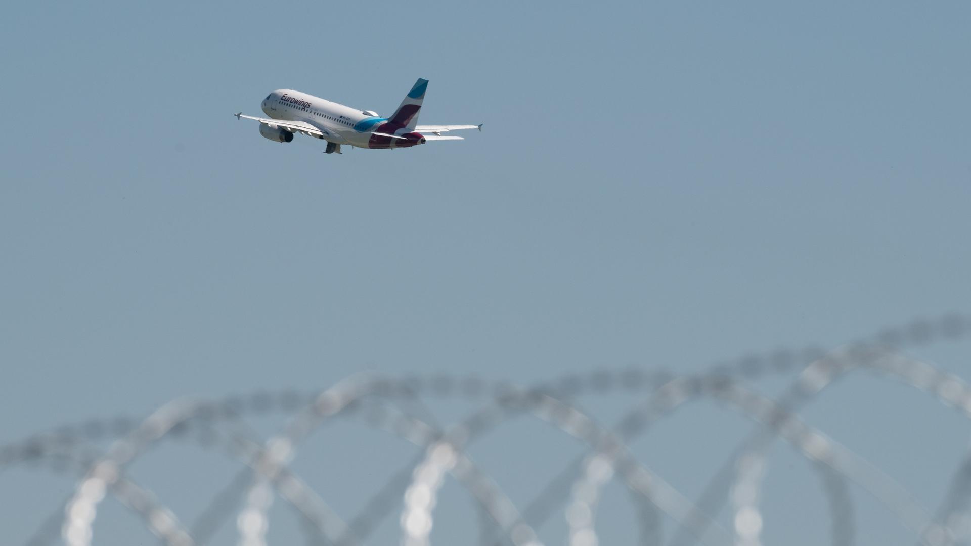 Ein Flugzeug von Eurowings startet am Flughafen Duesseldorf, im Vordergrund Stacheldraht Ein Flugzeug von Eurowings startet am Flughafen Duesseldorf, im Vordergrund Stacheldraht