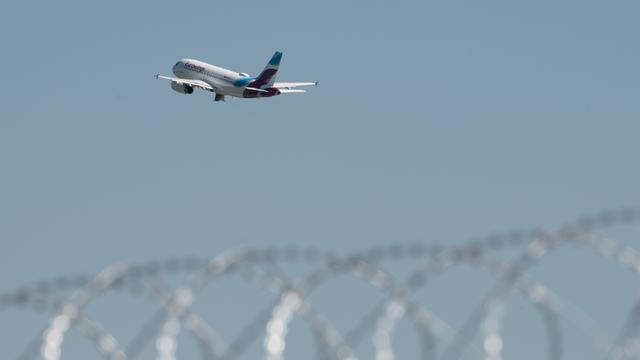 Ein Flugzeug von Eurowings startet am Flughafen Duesseldorf. Im Vordergrund ist Stachel-Draht zu sehen.