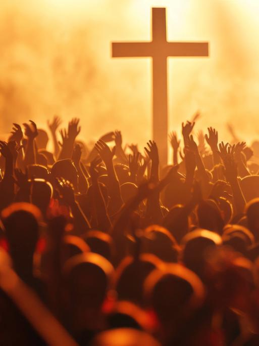 Eine Menschenmasse wie auf einem Rockkonzert tanzt um ein christliches Kreuz. (Bild von KI generiert.)