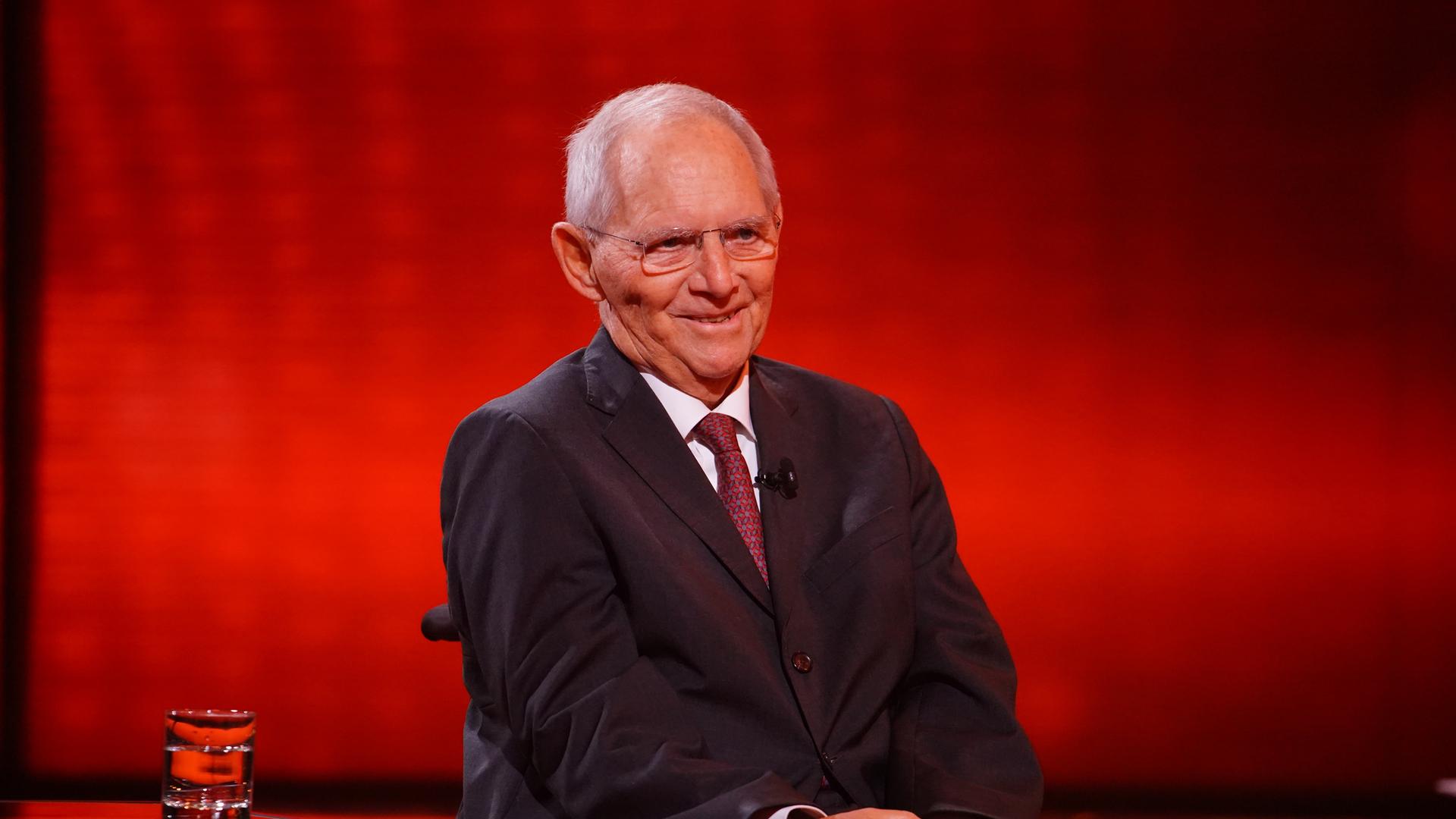 Das Foto von Ende 2021 zeigt Wolfgang Schäuble im Rollstuhl vor einem roten Hintergrund.