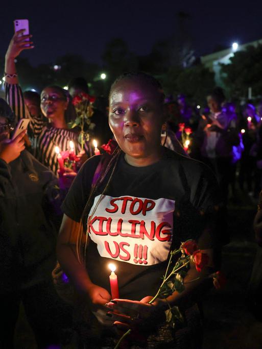 Aktivistinnen strecken Kerzen und rote Rosen in die Höhe, eine Mahnwache zum Gedenken an junge Frauen, die bei geschlechtsspezifischer Gewalt ums Leben gekommen sind. Nairobi, 14. Februar 2024.