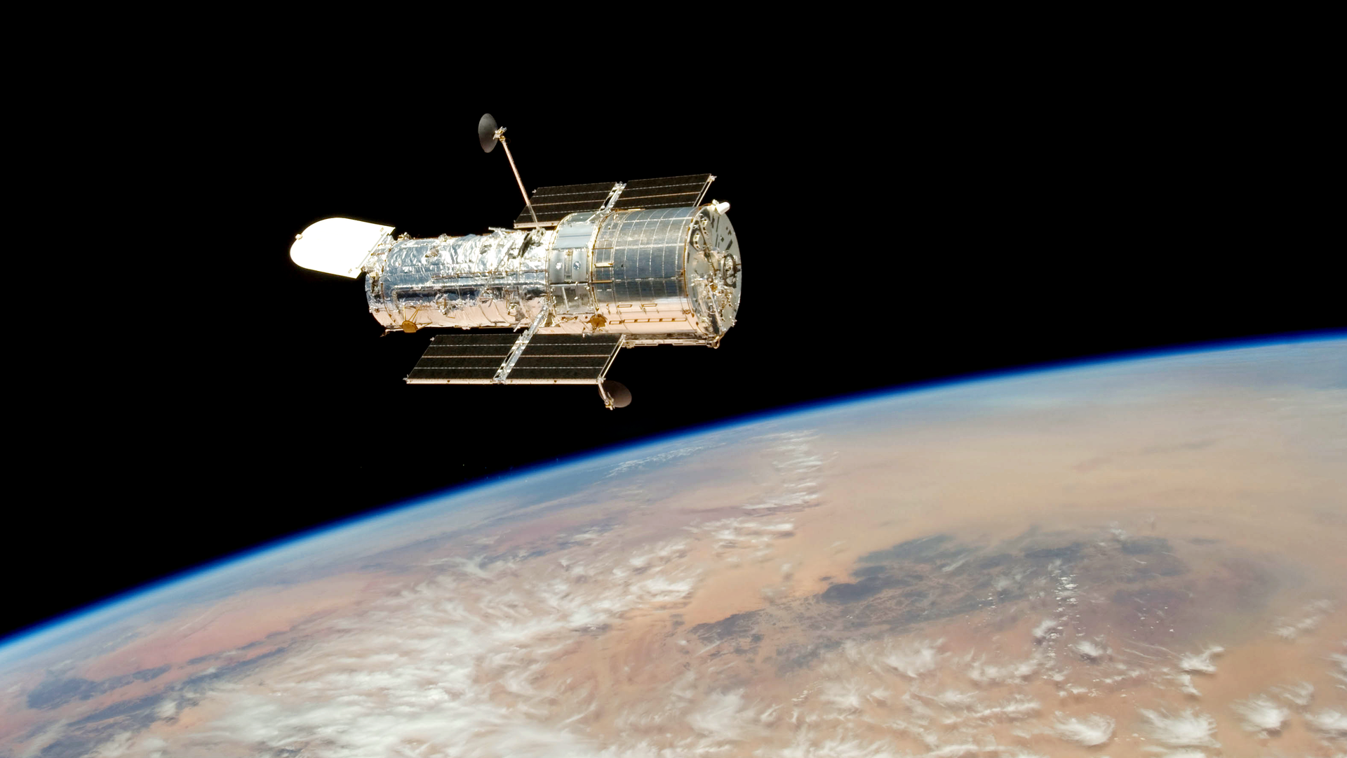 Das Hubble-Teleskop schwebt im Weltraum über der Erde.