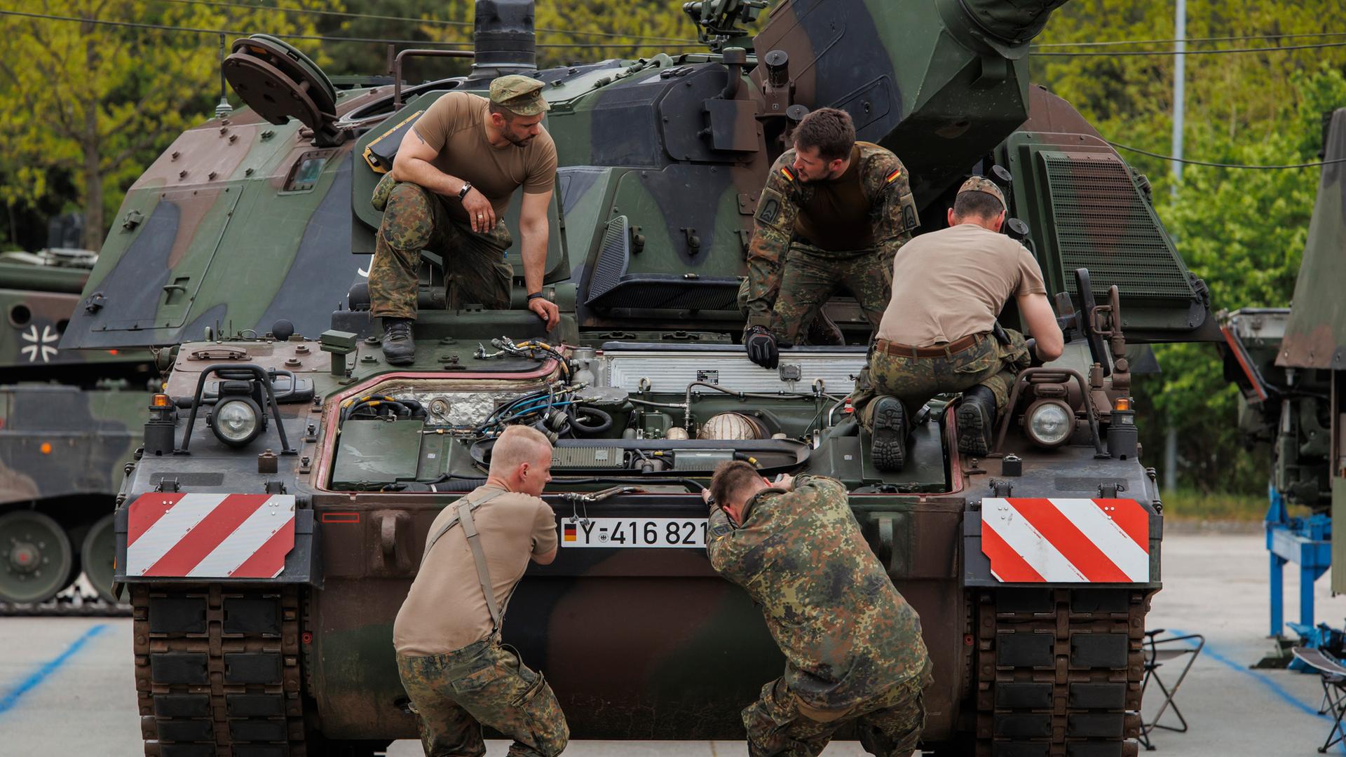 Eine Gruppe von fünf Soldaten arbeiten an einem Panzer.
