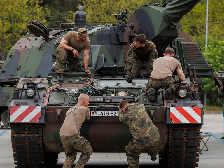 Eine Gruppe von fünf Soldaten arbeiten an einem Panzer.