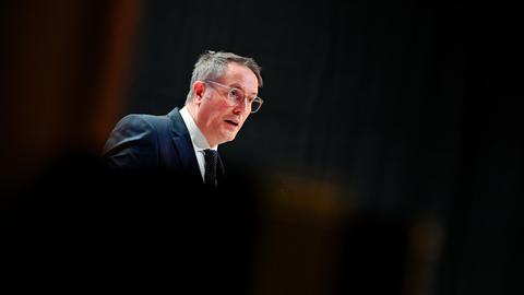 Alexander Schweitzer steht in dunkler Umgebung an einem Rednerpult und spricht.