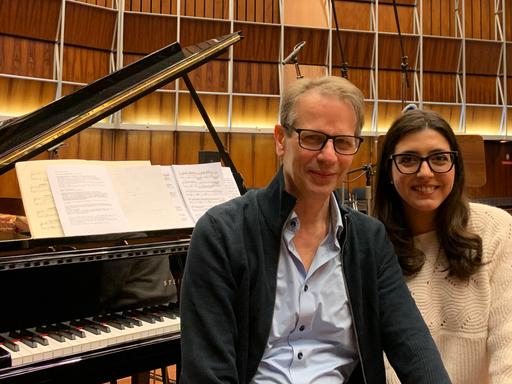 Christoph Schmitz sitzt neben Sophie Pacini auf einer Klavierbank vor dem aufgeklappten Flügel im Kammermusiksaal Köln.