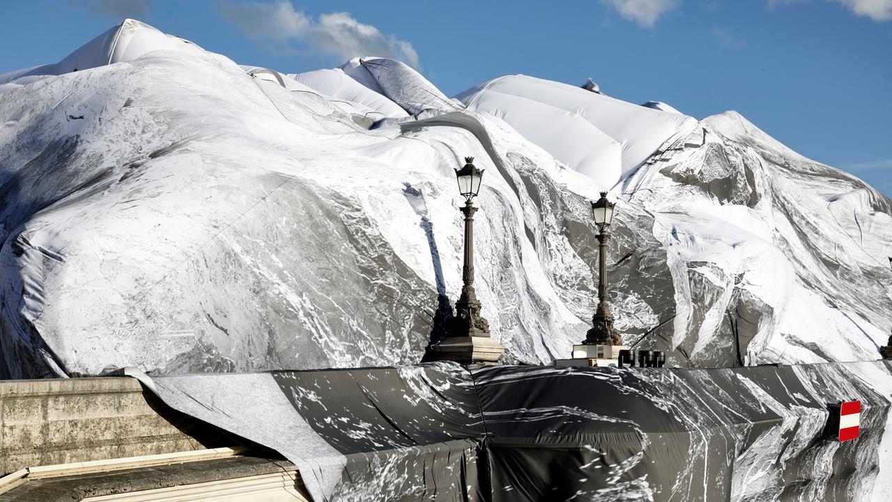 Das Bild zeigt ein Plane, die sich über die Brücke zieht. Darauf ist eine Höhlenlandschaft zu sehen. Im Vordergrund sind Straßenlaternen zu erkennen.