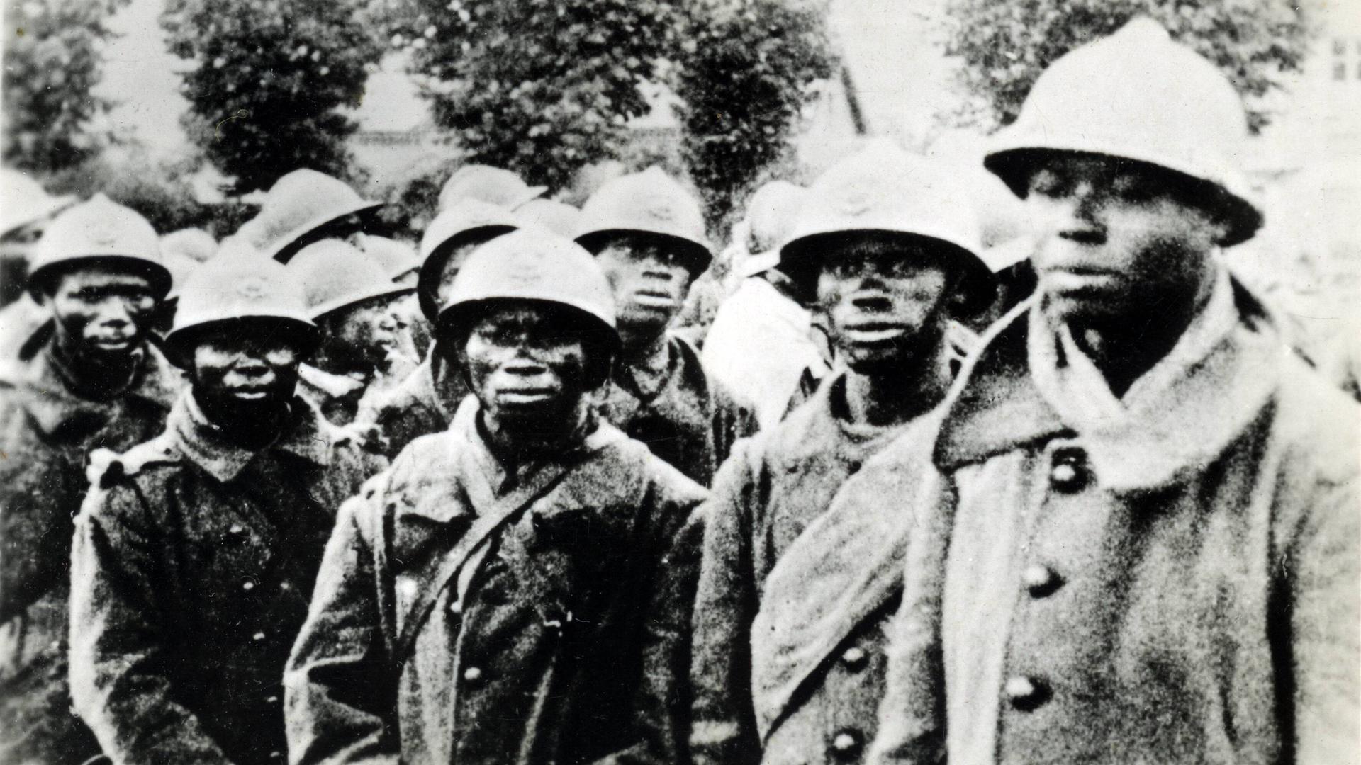 Eine Gruppe Soldaten afrikanischer Abstammung stehen mit militärischer Kleidung eng beieinander und schauten besorgt in die Kamera. Eine Gruppe Soldaten afrikanischer Abstammung stehen mit militärischer Kleidung eng beieinander und schauten besorgt in die Kamera.