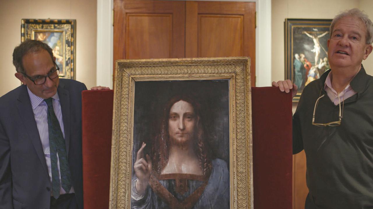 Zwei Männer stehen neben dem Gemälde "Salvator Mundi", das den Erlöser Christus zeigt.