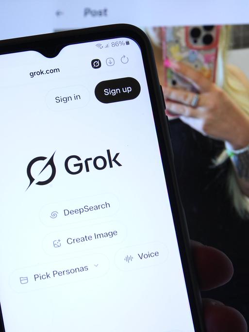 Auf einem Smartphone wurde der Chatbot Grok von Tech-Milliardär Elon Musk aufgerufen. Dahinter wurde auf einem Laptop der Kurznachrichtendienst X vormals Twitter aufgerufen, der ebenfalls Musk gehört.