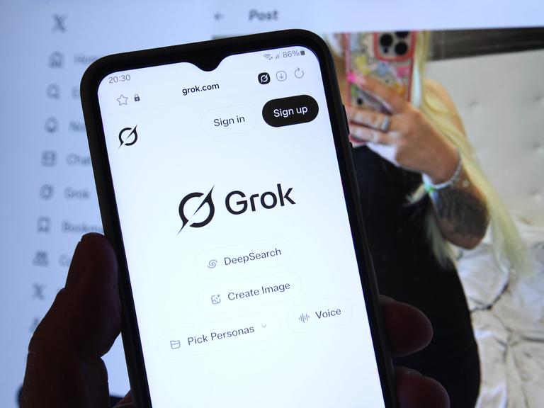 Auf einem Smartphone wurde der Chatbot Grok von Tech-Milliardär Elon Musk aufgerufen. Dahinter wurde auf einem Laptop der Kurznachrichtendienst X vormals Twitter aufgerufen, der ebenfalls Musk gehört.