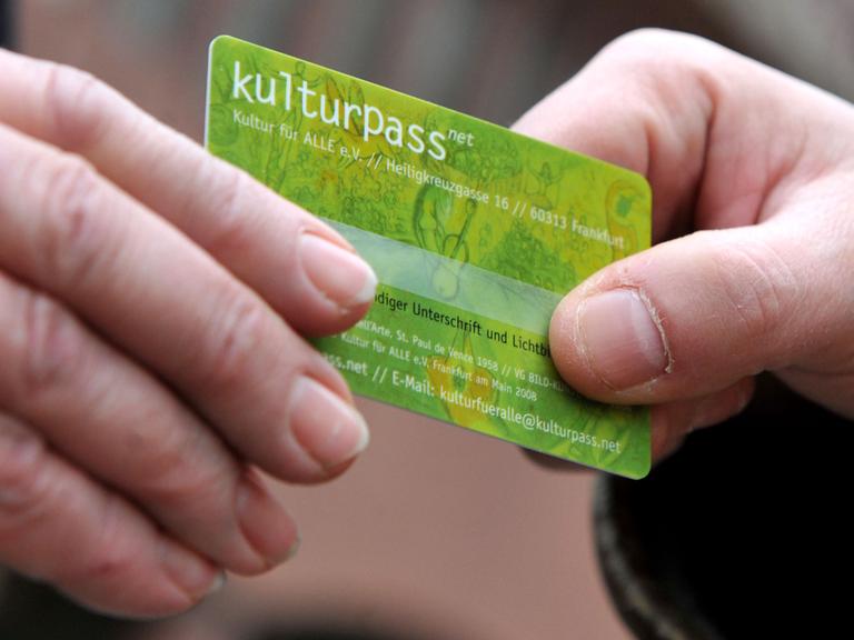 Zwei Männer halten vor einem Museum in Frankfurt am Main einen Kulturpass in den Händen. Der Kulturpass soll es Arbeitslosen und Menschen mit geringem Einkommen ermöglichen, Kulturveranstaltungen in Frankfurt und Umgebung zu einem deutlich reduzierten Eintrittspreis zu besuchen.