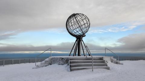Eine Globus Skulptur der Erdkugel steht am Nordkap in Norwegen auf Schnee und Eis.