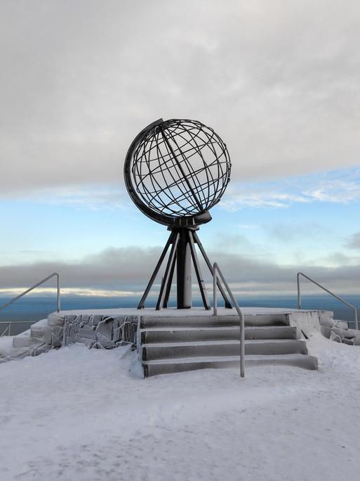 Eine Globus Skulptur der Erdkugel steht am Nordkap in Norwegen auf Schnee und Eis.