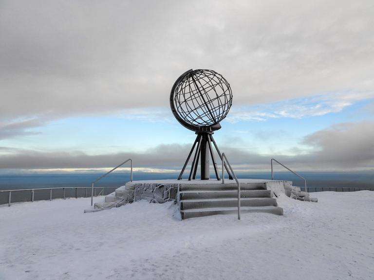 Eine Globus Skulptur der Erdkugel steht am Nordkap in Norwegen auf Schnee und Eis.