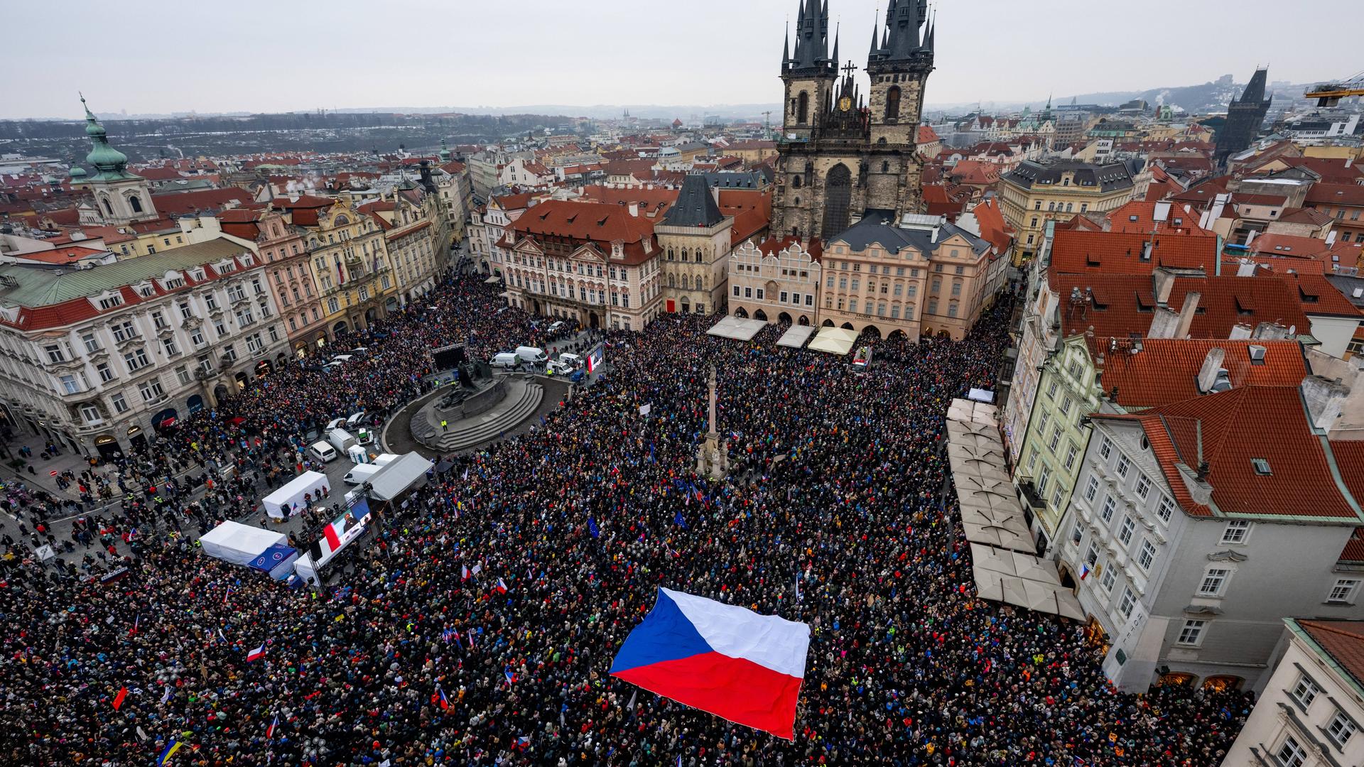 Ein Blick von oben auf einen großen Platz, der mit Zehntausenden Menschen gefüllt ist. Einige Menschen haben eine große Tschechien-Flagge über sich gespannt. Ein Blick von oben auf einen großen Platz, der mit Zehntausenden Menschen gefüllt ist. Einige Menschen haben eine große Tschechien-Flagge über sich gespannt.