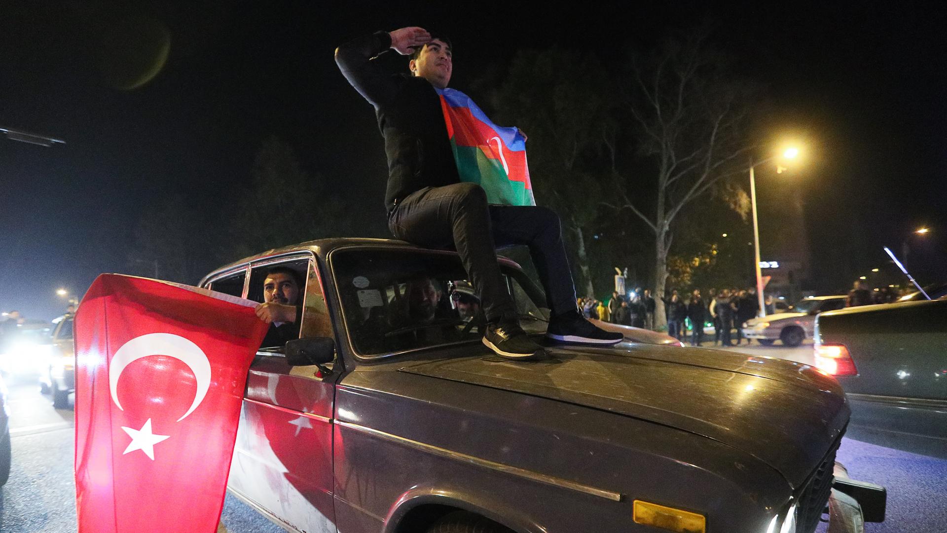 Menschen halten die Fahnen von der Türkei und Aserbaidschan aus dem Auto.