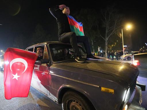 Menschen halten die Fahnen von der Türkei und Aserbaidschan aus dem Auto.