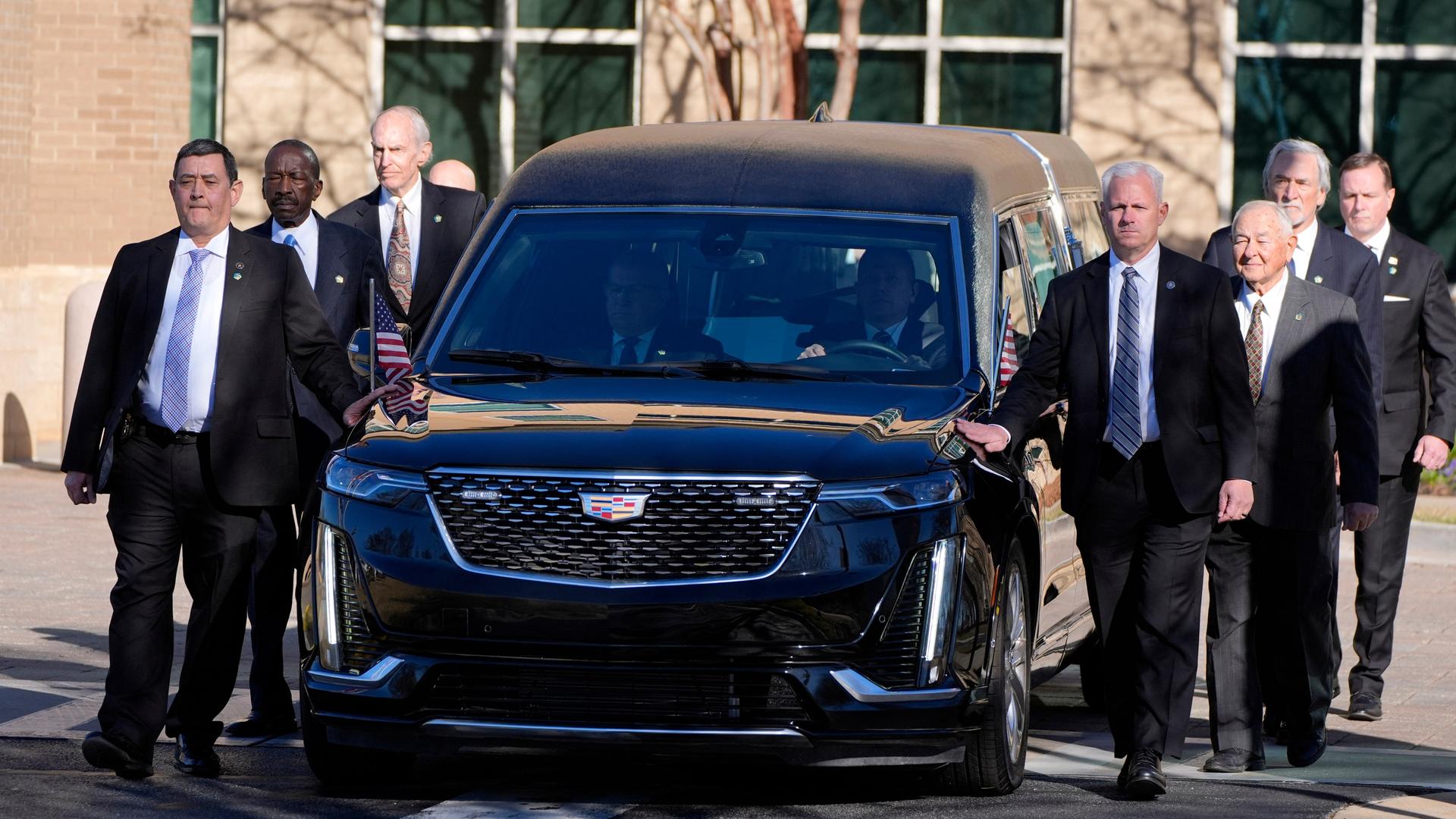 Frühere und ehemalige Mitarbeiter des US-amerikanischen Secret Service begleiten den Leichenwagen des früheren US-Präsidenten Jimmy Carter.