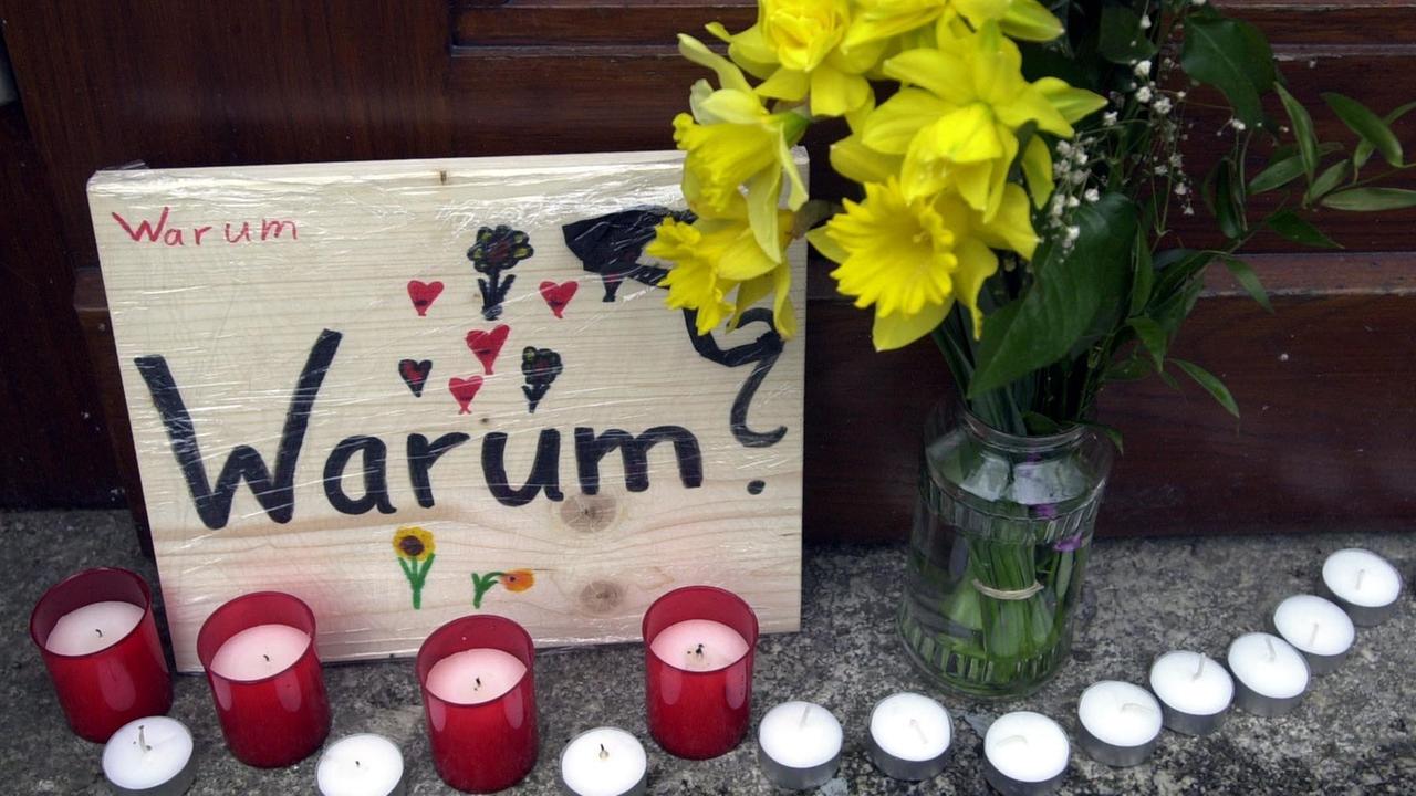 Blumen, Kerzen und ein Schild mit der Aufschrift "Warum?" stehen am 26.04.2002 in Erfurt an einem Eingang des Gutenberg-Gymnasiums in Erfurt. In einem entsetzlichen Amoklauf hatte ein ehemaliger Schüler in diesem Gymnasium 16 Menschen und sich selbst erschossen.
