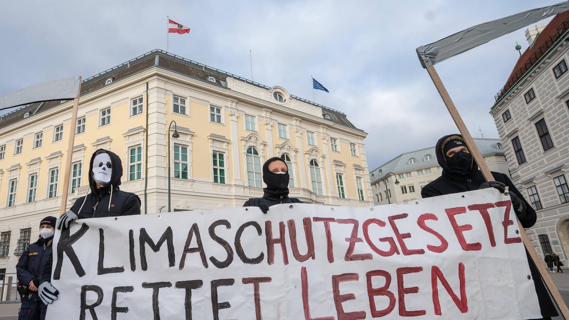 Drei maskierte Kundgebungsteilnehmer halten ein Transparent mit der Aufschrift: "Klimaschutzgesetz rettet Leben".