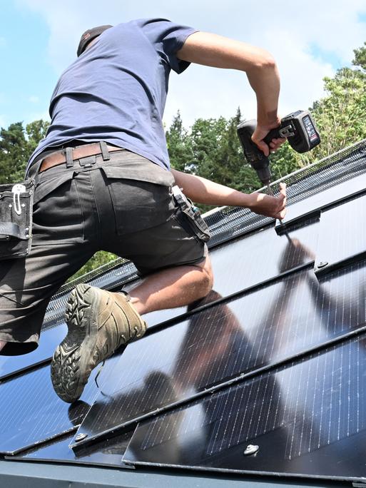 Ein Mann arbeiten an einem Photovoltaik-Modul auf einem Dach 