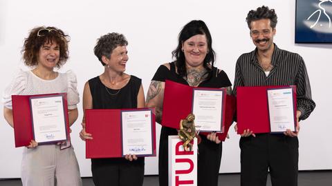 Kelag-Preisträgerin Kinga Toth, 3sat-Preisträgerin Magdalena Schrefel, Bachmannpreisträgerin Lena Schätte und Deutschlandfunk-Preisträger Ozan Zakariya Keskinkilic halten lächelnd ihre Urkunden in die Kamera