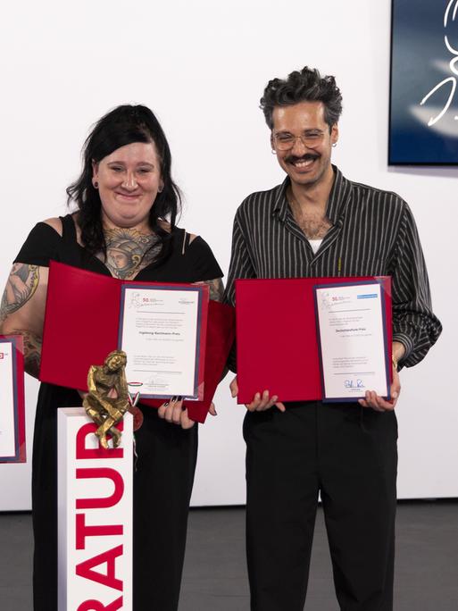Kelag-Preisträgerin Kinga Toth, 3sat-Preisträgerin Magdalena Schrefel, Bachmannpreisträgerin Lena Schätte und Deutschlandfunk-Preisträger Ozan Zakariya Keskinkilic halten lächelnd ihre Urkunden in die Kamera