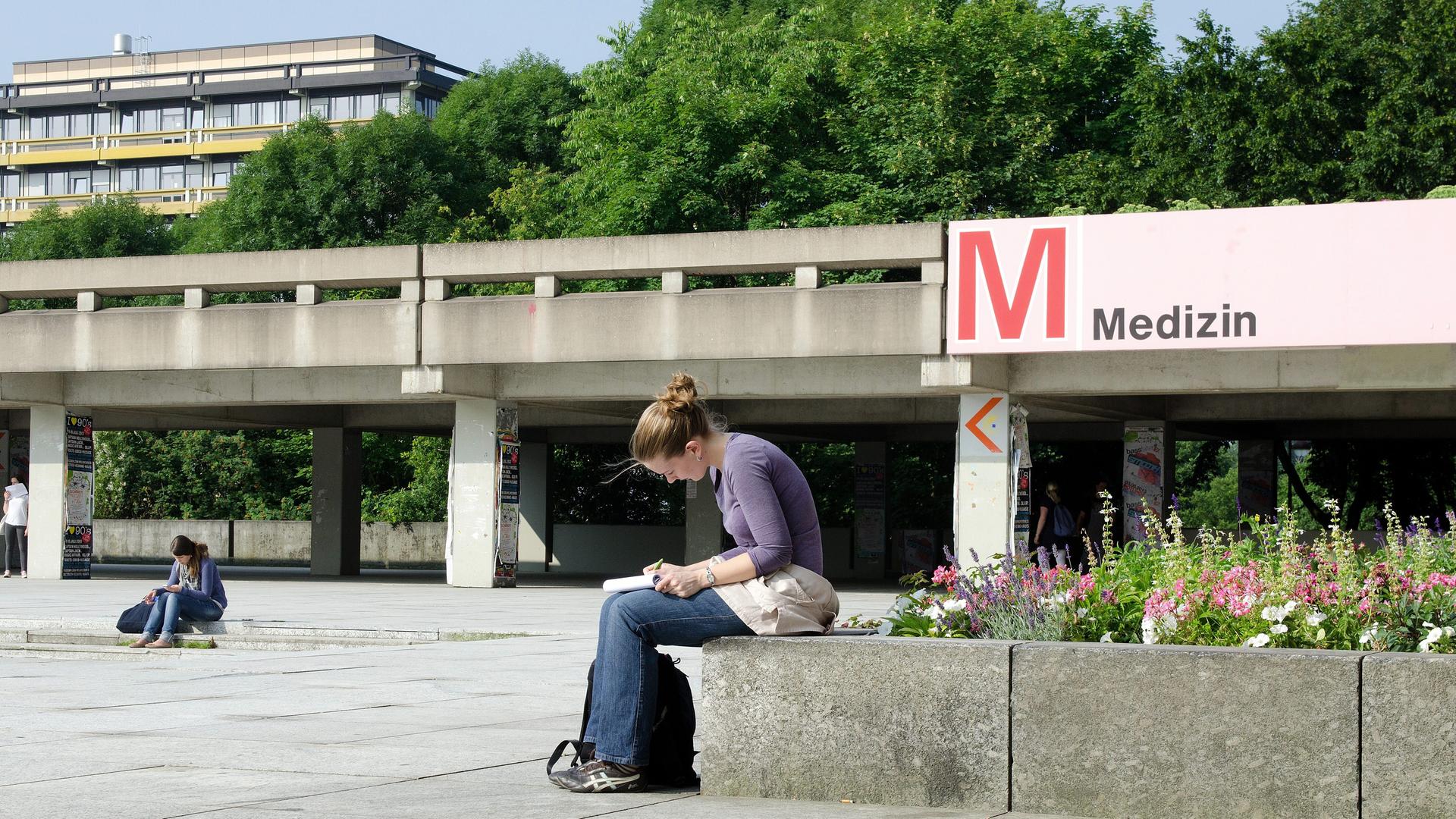 Eine Medizin-Studentin in einer Vorlesungspause auf dem Campus: Sie ist über ihre Notizen gebeugt.