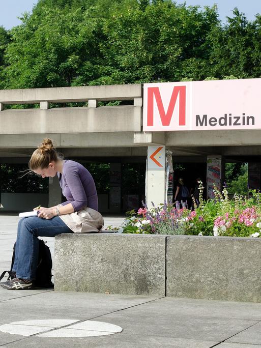 Eine Medizin-Studentin in einer Vorlesungspause auf dem Campus: Sie ist über ihre Notizen gebeugt. Eine Medizin-Studentin in einer Vorlesungspause auf dem Campus: Sie ist über ihre Notizen gebeugt.