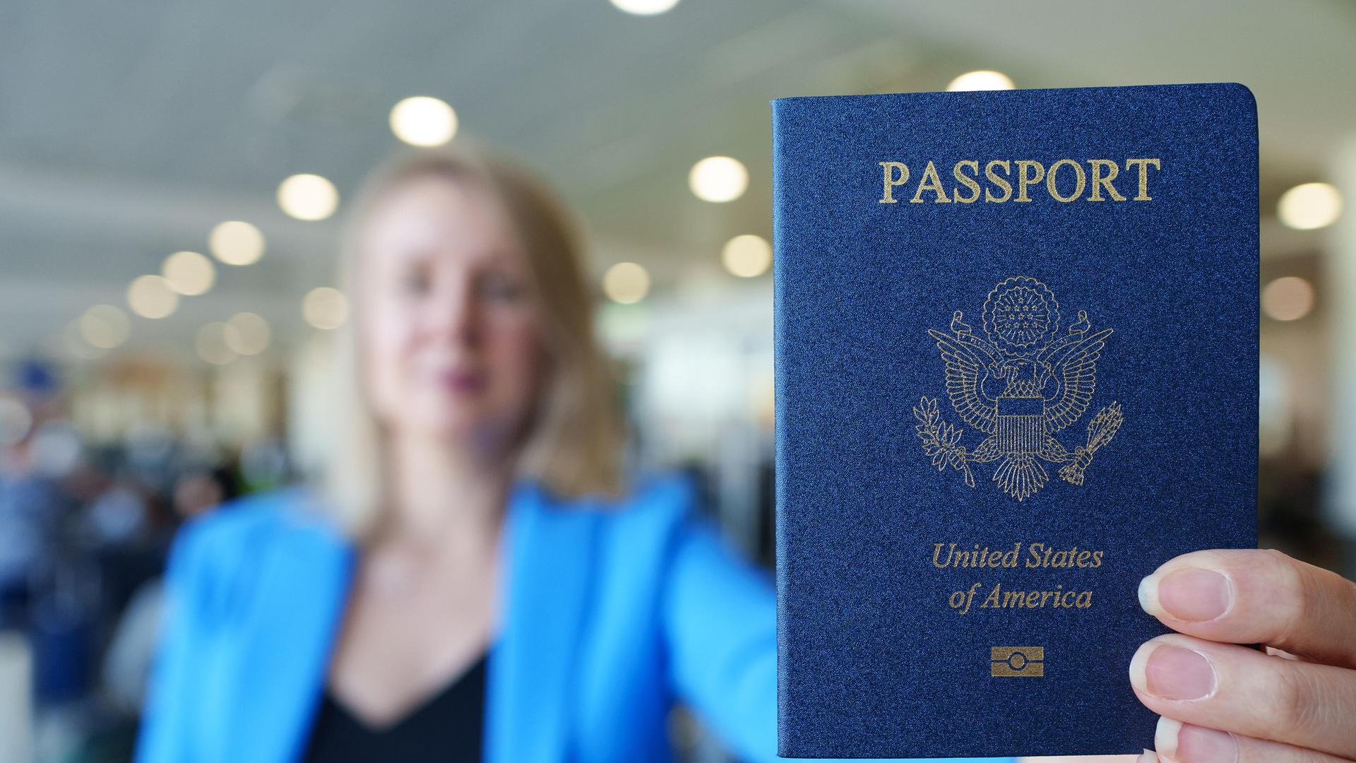Eine Frau zeigt ihren US-amerikanischen Reisepass mit ausgestrecktem Arm. Eine Frau zeigt ihren US-amerikanischen Reisepass mit ausgestrecktem Arm.