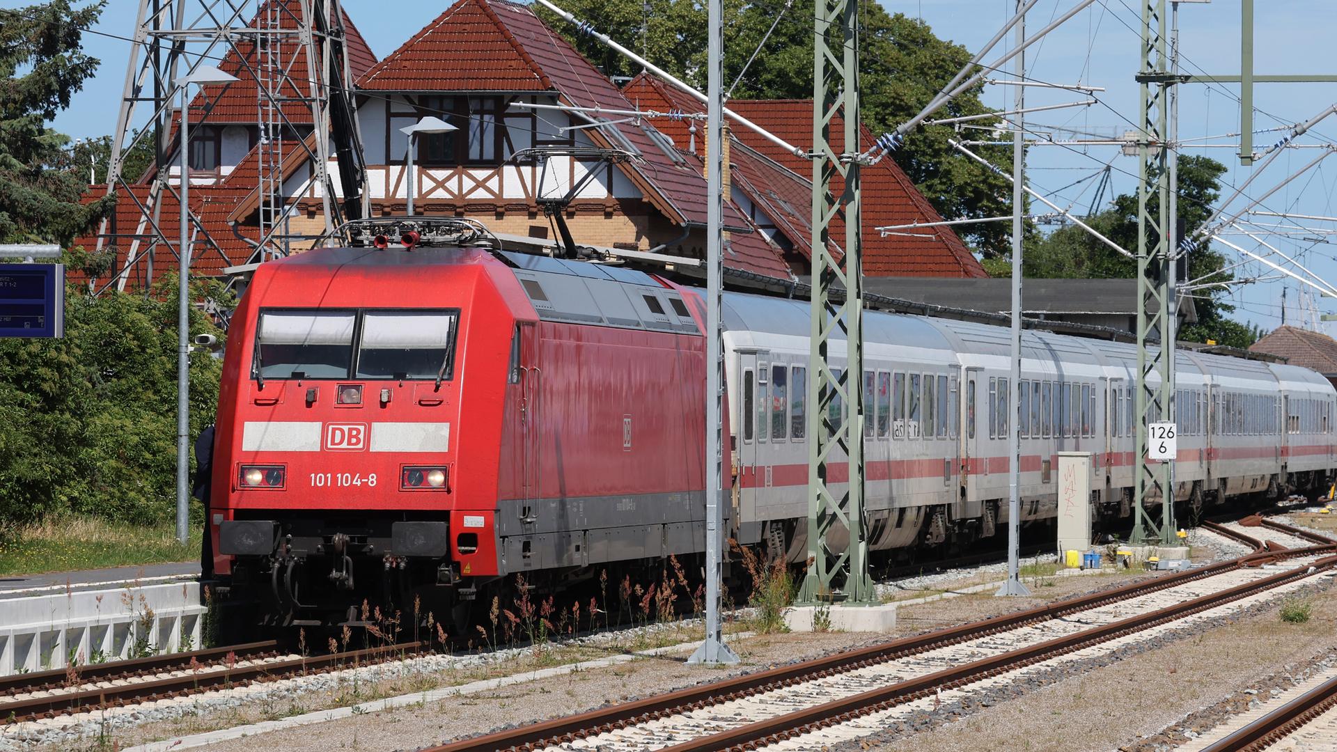 Ein Intercity fährt an einem Fachwerkhaus vorbei, das direkt an den Schienen gelegen ist.