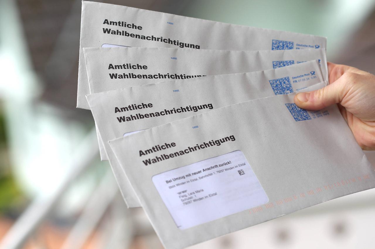 Eine Hand hält vier Brief-Umschläge. Darauf steht: "Amtliche Wahlbenachrichtigung".