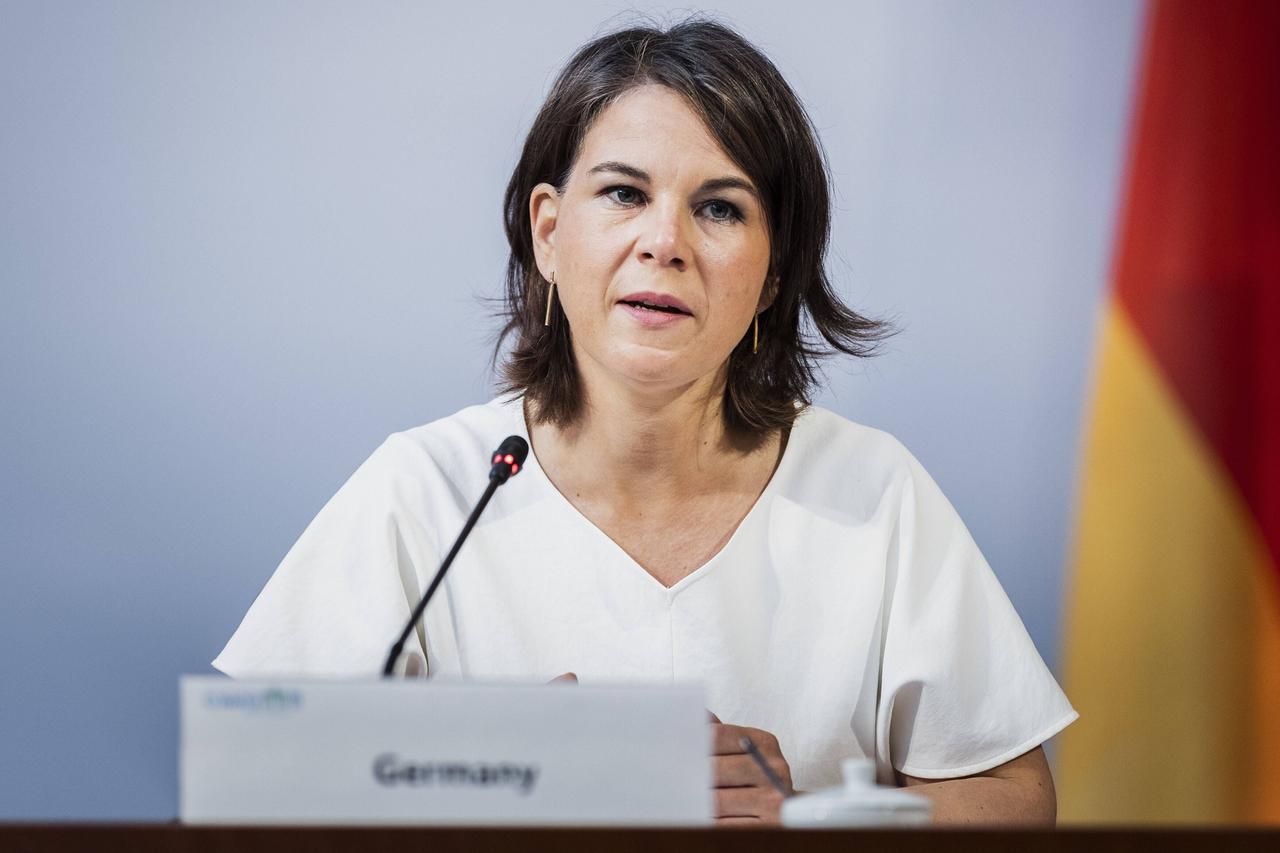 Annalena Baerbock, Bundesaußenministerin, aufgenommen im Rahmen des Petersberger Klimadialoges im Auswärtigen Amt in Berlin sitzt hinter einem Mikrofon. Vor ihr verschwommen ein Schild mit der Aufschrift "Germany".