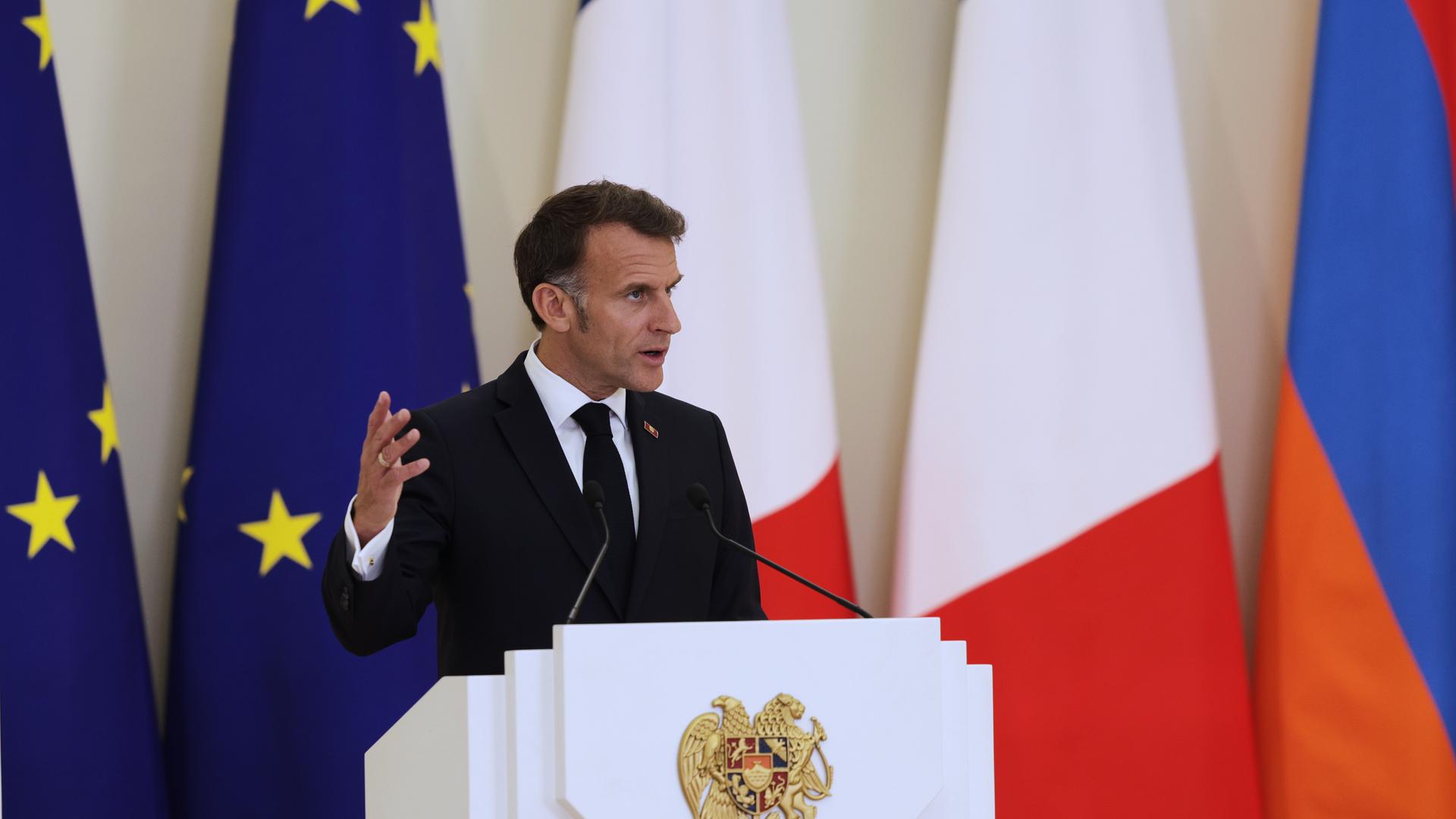 Frankreichs Präsident Macron spricht beim EU-Armenien-Gipfel in Jerewan an einem Redepult. Dahinter sind mehrere Fahnen.