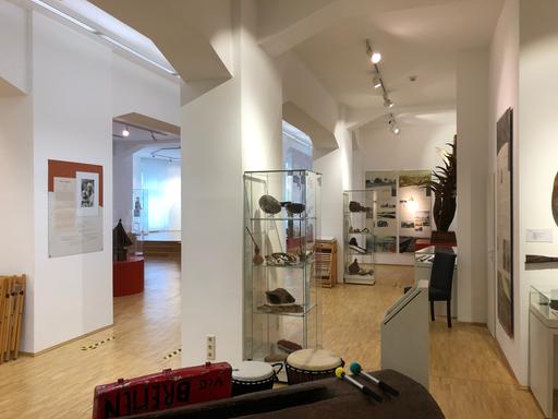 Museumraum mit zahlreichen Ausstellungsstücken aus Afrika, Asien und Ozeanien in Vitrinen und auf Sockeln.
