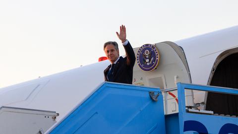 Blinken winkt, als er aus seinem Flugzeug steigt. 