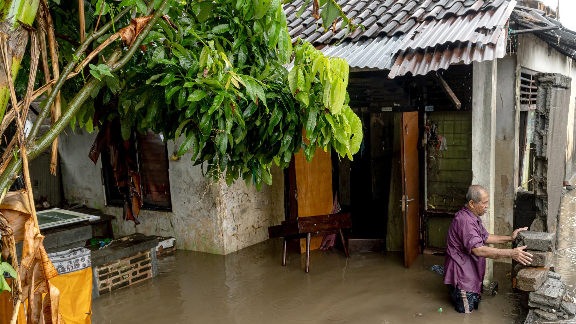 Ein Mann steht in der Nähe seines überschwemmten Hauses, nachdem Denpasar, Bali, von starken Regenfällen heimgesucht wurde. Ein Mann steht in der Nähe seines überschwemmten Hauses, nachdem Denpasar, Bali, von starken Regenfällen heimgesucht wurde.