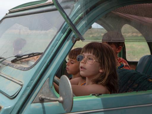 Drei Kinder sitzen in einem alten Auto