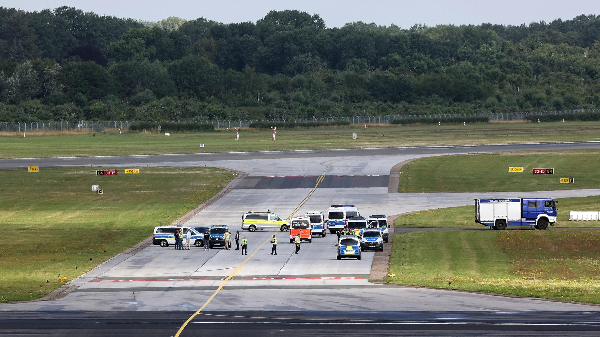 Einsatzkräfte der Polizei stehen auf einem Rollfeld des Hamburger Flughafens.