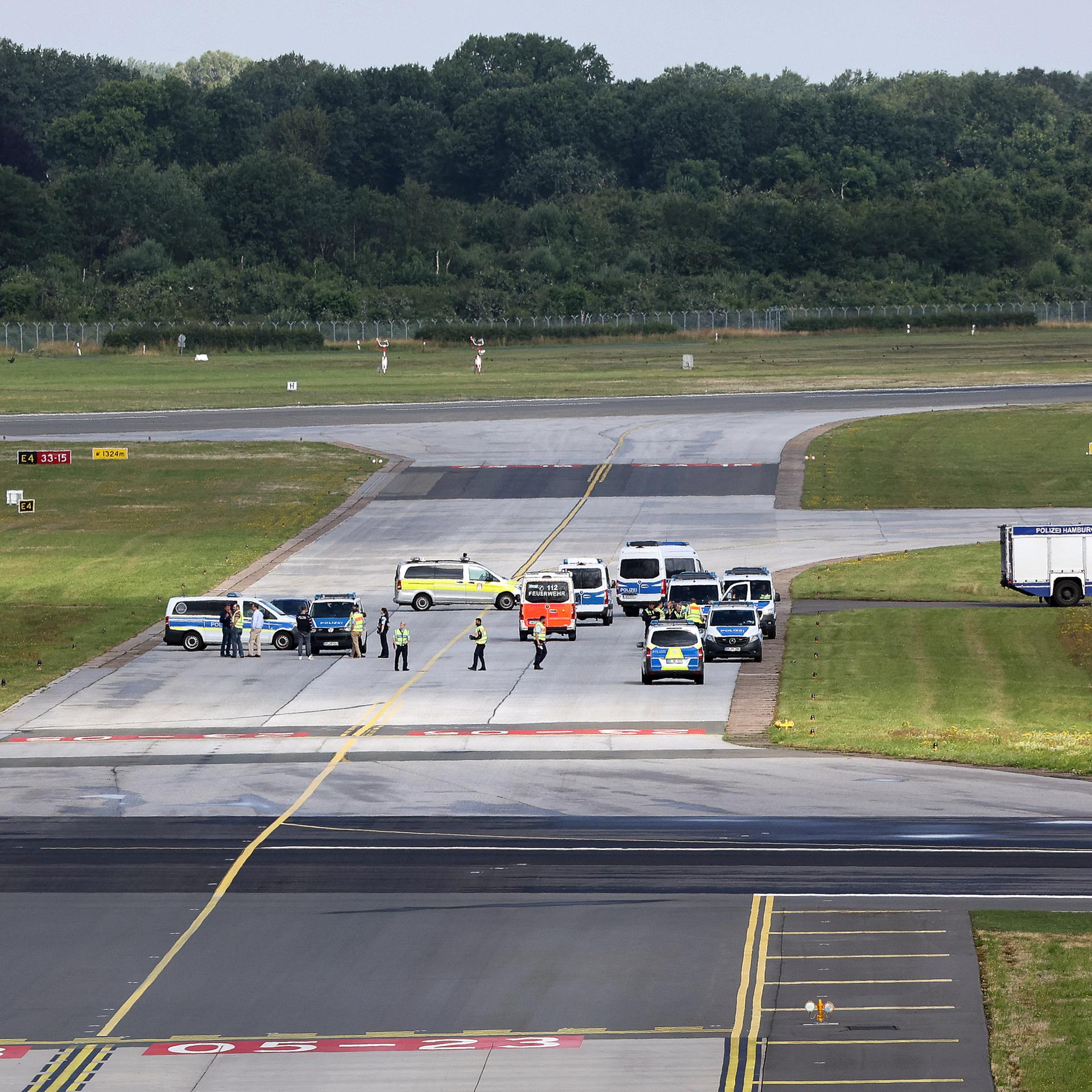 Einsatzkräfte der Polizei stehen auf einem Rollfeld des Hamburger Flughafens.