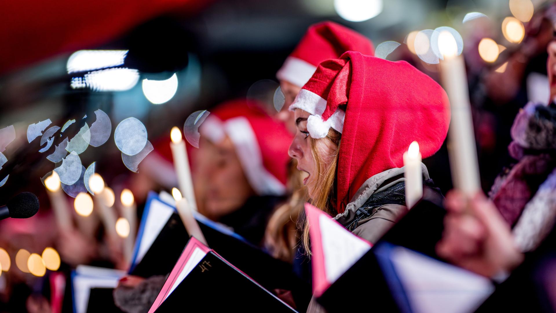 Menschen mit Weihnachtsmützen singen Weihnachtslieder in einem Stadion