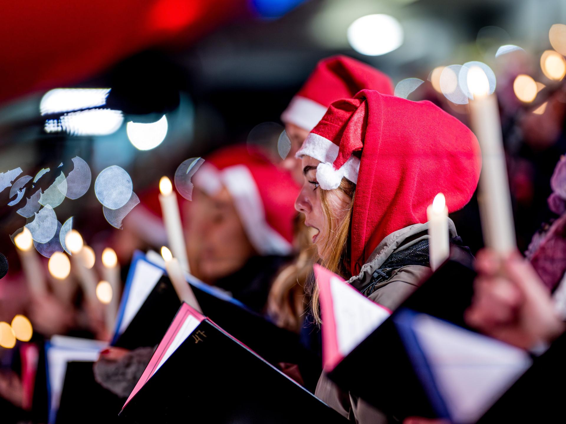 Menschen mit Weihnachtsmützen singen Weihnachtslieder in einem Stadion